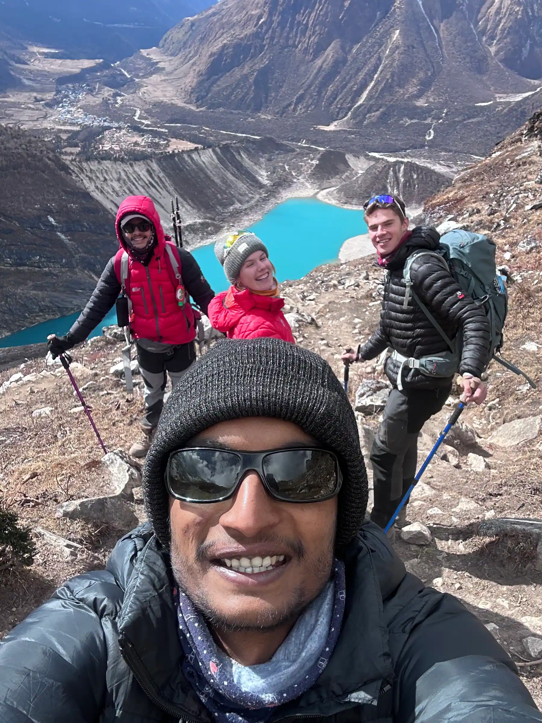Trekkers on the Manaslu Base Camp trail above Birendra Lake, with Samagaun in the valley behind