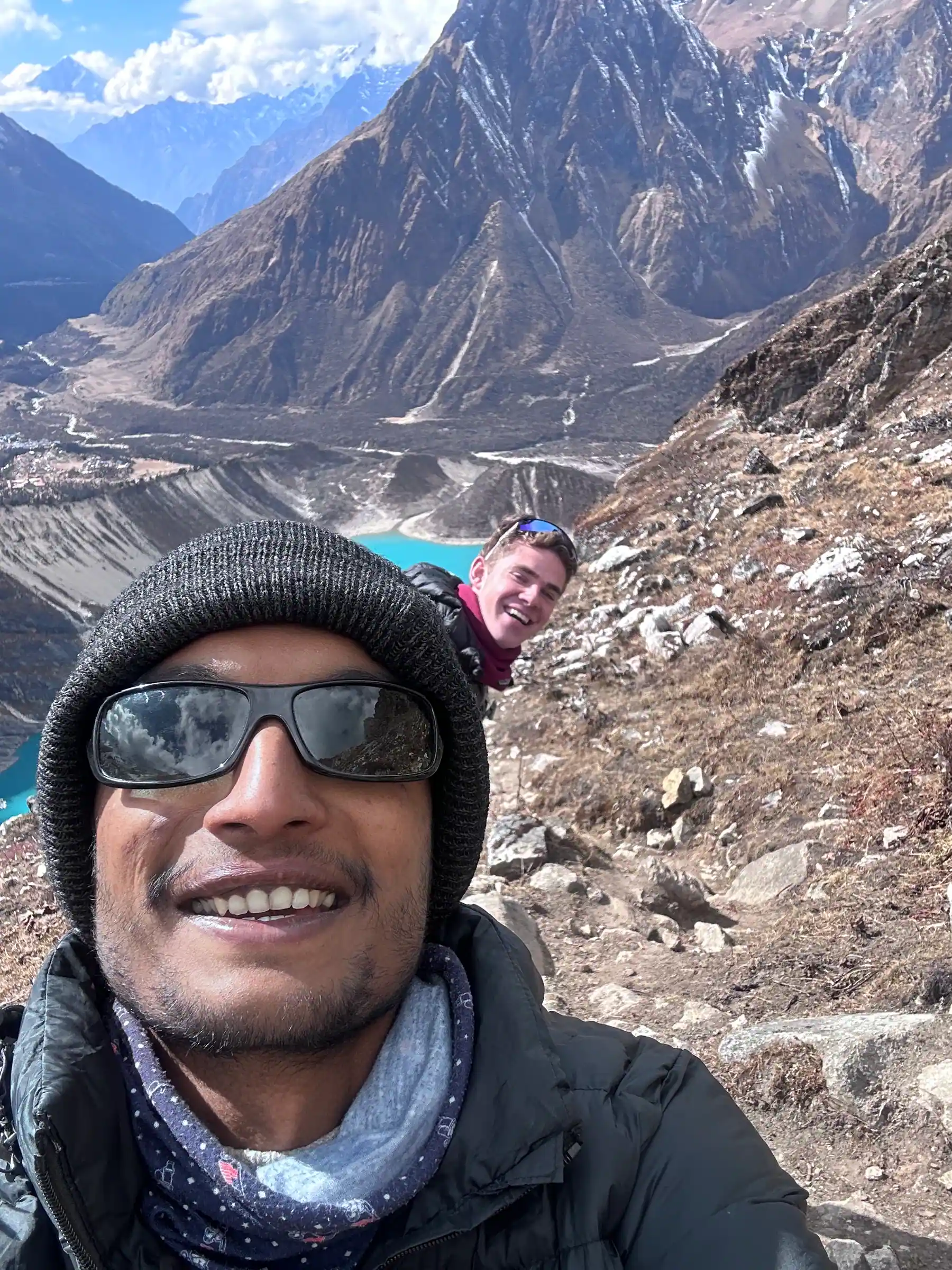 A 6K Nepal Treks guide and a trekker on the trail to Manaslu Base Camp, Birendra Lake and Samagaun in the valley below