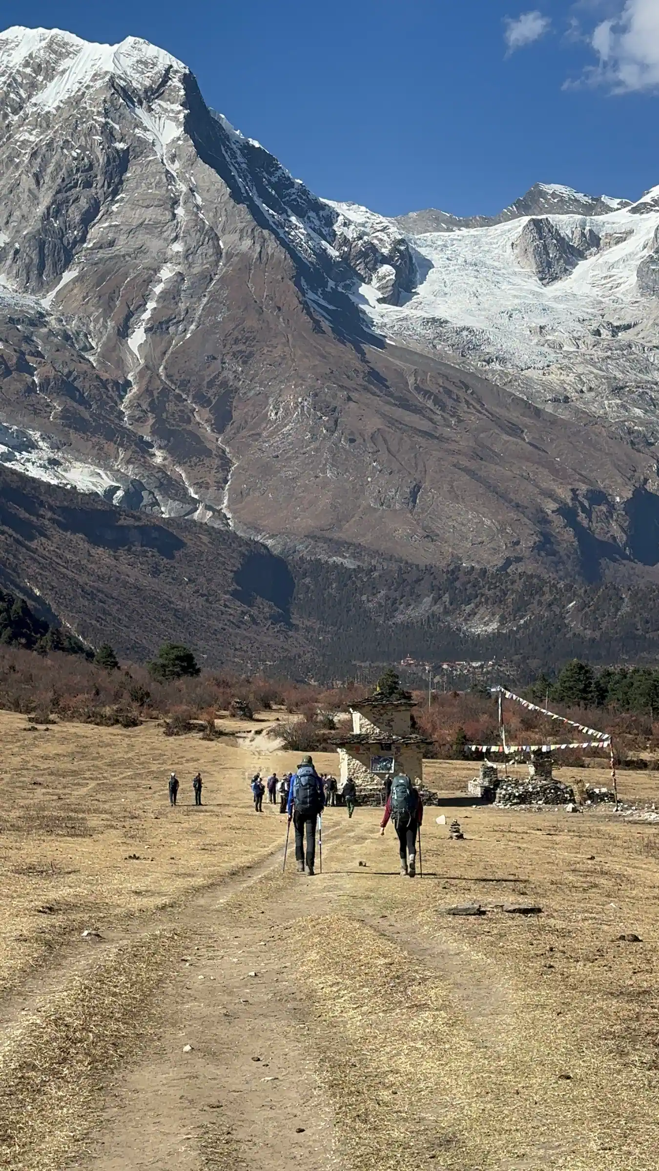 Trekkers walking towards the chorten and prayer flags on the approach to Samagaun